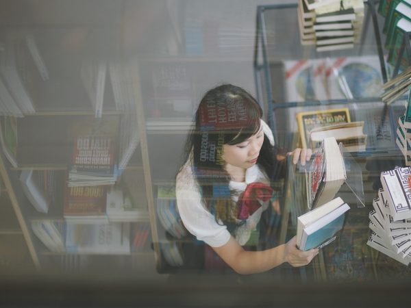 物理实验读者运营何小满在桌前分类整理读者来信与纠错截图，屏幕旁贴着待处理事项便签